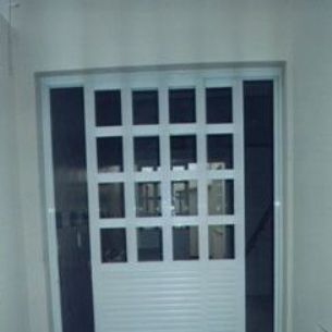 Porta de abrir com painel inferior em veneziana e parte superior quadriculada com 2 painis fixos laterais.
